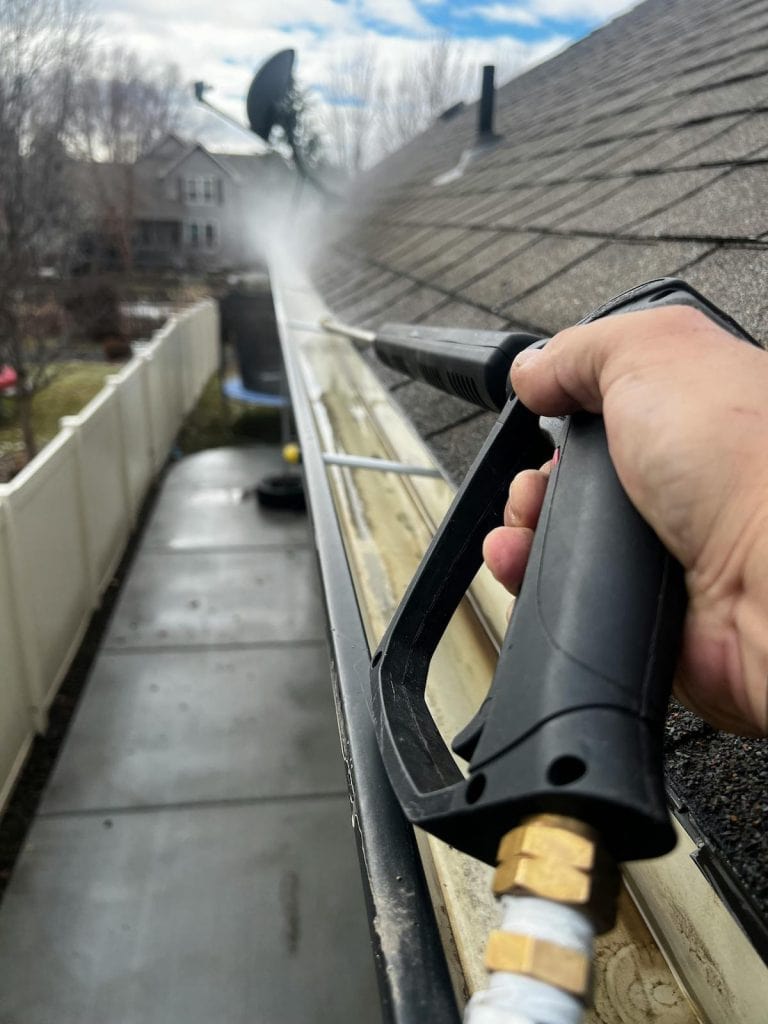 Professional gutter cleaning removing leaves and debris from gutters in St. Thomas Ontario